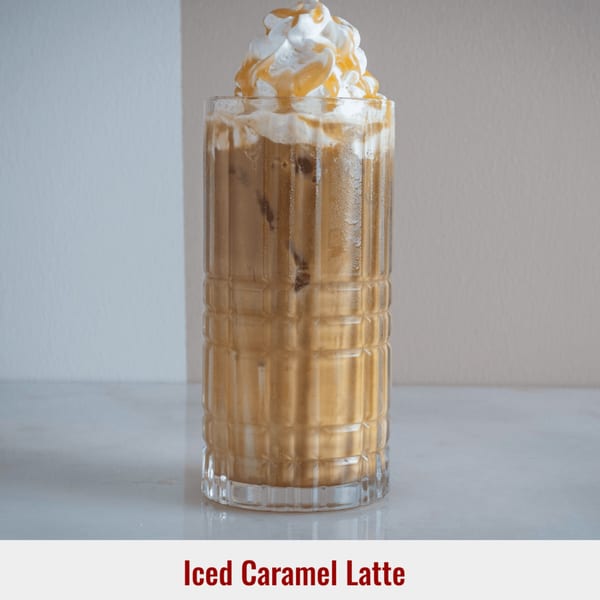 Iced caramel latte in a tall glass, topped with whipped cream and caramel drizzle.