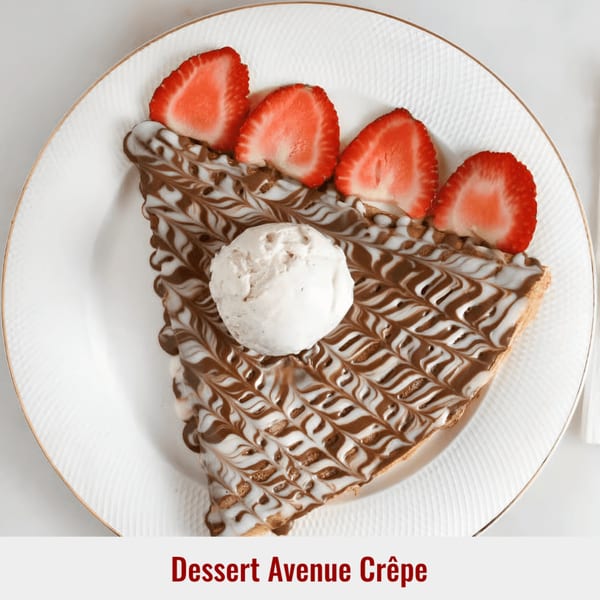 Dessert Avenue Crêpe with chocolate and white sauce drizzle, topped with a scoop of ice cream and strawberries.